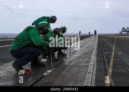 PHILIPPINISCHE SEE (5. April 2022) Seeleute stecken Knöpfe in ein Katapult (Gleis) auf dem Cockpit des Flugzeugträgers der Nimitz-Klasse USS Abraham Lincoln (CVN 72). Die Abraham Lincoln Strike Group befindet sich in einem geplanten Einsatz im US-7.-Flottenbereich, um die Interoperabilität durch Allianzen und Partnerschaften zu verbessern und gleichzeitig als einsatzbereite Truppe zur Unterstützung einer freien und offenen Region Indo-Pacific zu fungieren. Stockfoto