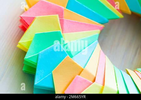 Farbenfroher Origami-Ring auf weißem Tischhintergrund, abstrakte parametrische Struktur aus Papierblättern, Nahaufnahme mit selektivem Weichzeichner Stockfoto