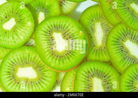 Nahaufnahme von Kiwis in Flüssigkeit mit Blasen. Scheiben von gren-reifen Kiwis im Wasser. Nahaufnahme frischer Scheiben grüner Kiwis auf weißem Hintergrund. Bis Stockfoto
