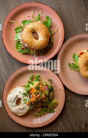 Vertikal verschiedene köstliche Sesam Donuts Burger mit Käse, Fleischfüllung, Grünfüllung, Sauce serviert auf Tellern Stockfoto