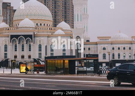 Astana, Kasachstan - 23. November 2022: Menschen warten auf öffentliche Verkehrsmittel. Beheizte Bushaltestellen mit Klimaanlage. Warm im Winter, kühl im Sommer. Stockfoto