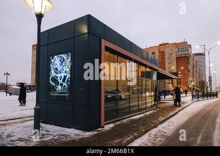 Astana, Kasachstan - 23. November 2022: Menschen warten auf öffentliche Verkehrsmittel. Beheizte Bushaltestellen mit Klimaanlage. Warm im Winter, kühl im Sommer. Stockfoto