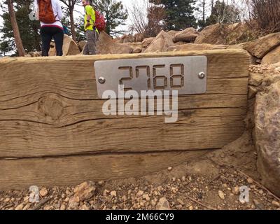 An einer der Stufen des Manitou Incline in Manitou Springs, Colorado, ist eine Markierung angebracht. Die Steigung ist eine Treppenwanderung auf einen Berg, und Wanderer, die den Gipfel erreichen, sehen diese Plakette, die insgesamt 2.768 Stufen zählt und einen Blick auf die Städte und die Tierwelt darunter bietet. Stockfoto