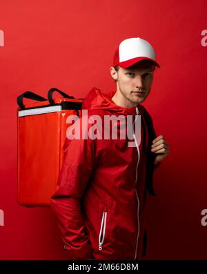 Liefermann mit Thermo-Rucksack, der vor der Kamera lächelt. Lebensmittellieferservice. Schnelle Expresslieferung nach Hause. Online-Bestellung. Stockfoto