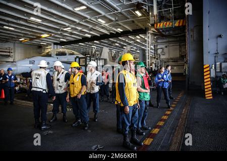 PHILIPPINISCHE SEE (7. April 2022) Seeleute, die während einer Wiederauffüllung auf See mit dem Flottenöler USNS Tippecanoe (T-AO 199) in der Hangarbucht an Bord des Flugzeugträgers USS Abraham Lincoln der Nimitz-Klasse (CVN 72) auf Fracht bereitstehen. Die Abraham Lincoln Strike Group befindet sich in einem geplanten Einsatz im US-7.-Flottenbereich, um die Interoperabilität durch Allianzen und Partnerschaften zu verbessern und gleichzeitig als einsatzbereite Truppe zur Unterstützung einer freien und offenen Region Indo-Pacific zu fungieren. Stockfoto