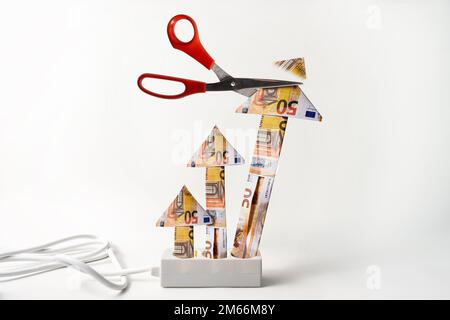 Konzept der Energiepreisbegrenzung (in Deutschland Strompreisbremse), Steckdosenleiste mit aufsteigenden Pfeilen aus Euro-Banknoten, die Spitze wird mit einer Schere abgeschnitten, Stockfoto