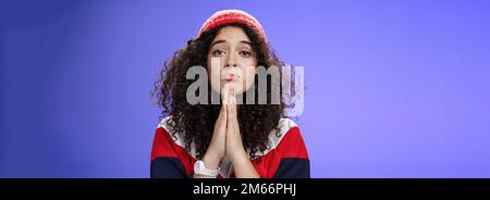 Nahaufnahme von niedlichen weiblichen Freundin Betteln bringen ihre Lieblings-Süßigkeiten halten Hände in beten Falten Lippen und starrte mit Engel unschuldigen Blick auf Stockfoto