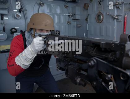 220408-N-VJ326-1158 PAZIFIK (8. April 2022) – Aviation Ordnanceman Airman Robert Douglass aus Ansonia, Conn., zielt auf ein Maschinengewehr mit einem Kaliber .50 während des von der Besatzung gedienten Fehlzündungstrainings auf dem Amphibienschiff USS Tripoli (LHA 7) vom April 8 ab. Tripoli führt gerade Routineeinsätze in der US-3.-Flotte durch. Stockfoto