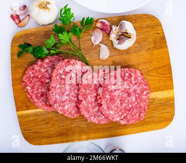 Kochzutaten, rohe Burgerschnitzel an Bord Stockfoto