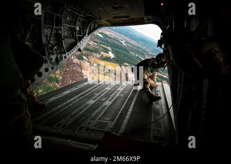 Soldaten der Washington National Guard mit 1. Bataillon, 168. General Support Aviation Regiment (GSAB), 96. Aviation Truppenkommando, Transport 1. Special Forces Group (Airborne) und kanadischen Partnern über Rogers Drop Zone auf der Joint Base Lewis-McChord, Washington, 6. Dezember 2022. Der gemeinsame statische Leitungssprung war Teil der jährlichen Menton Week 78., die anlässlich des Jahrestags der kombinierten Deaktivierung der US-amerikanischen und kanadischen First Special Service Force stattfand. (USA Army National Guard Foto von Staff Sgt. Adeline Witherspoon) Stockfoto