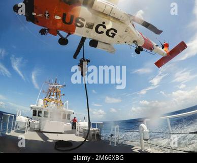 Ein Mitglied des Coast Guard Maritime Security Response Team East führt eine vertikale Einfügeentwicklung mit Crews von Coast Guard Cutter Pablo Valent und einer Coast Guard Air Station Clearwater MH-60 Jayhawk am 24. Mai 2022 durch. Die vertikale Einfügung kann in einer Vielzahl von Boarding-Szenarien verwendet werden und bietet der Küstenwache ein zusätzliches taktisches Tool zur Erfüllung von Strafverfolgungsmissionen. (USA Küstenwache Foto von Petty Officer 1. Class Logan Kellogg) Stockfoto