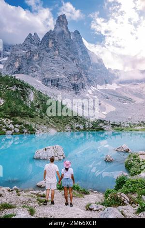 Paare wandern zum See Lago di Sorapis in den italienischen Dolomiten, türkisfarbenen Alpensee. Männer und Frauen stehen an einem türkisfarbenen See in den alpen Stockfoto