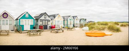 Panoramaszene mit einer Reihe farbenfroher Strandhütten inmitten von Sanddünen. Hengistbury Head, Dorset, Großbritannien Stockfoto