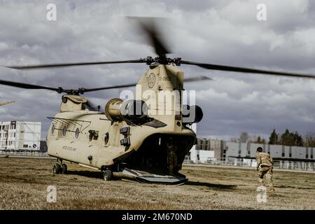 EIN US-AMERIKANISCHER Army CH-47 Chinook Helikopter vom 1-214. General Support Aviation Bataillon, 12. Combat Aviation Brigade wartet als US Der Soldat der Armee läuft am 8. April 2022 in der Landezone nahe der G2A Arena in Polen, um sich zu beladen, während einer gemeinsamen Übung unter der Leitung der polnischen Streitkräfte. Diese und andere Maßnahmen dieser Art verbessern unsere Interoperabilität mit unseren NATO-Verbündeten und -Partnern und stärken die regionalen Beziehungen, die wir aufgebaut haben. 12 CAB ist die einzige dauerhafte Luftfahrtbrigade in ganz Europa, die es uns ermöglicht, Bedrohungen aus jeder Richtung abzuwehren und abzuwehren.12 CAB ist am Stockfoto