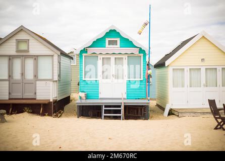 Eine Reihe von bunt bemalten Holzhütten an einem Sandstrand. Hengistbury Head, Dorset, Großbritannien Stockfoto