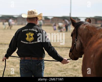 Ein Soldat, der der 4. Infanteriedivision zugeteilt wurde, und Fort Carson Mounted Color Guard führt ein Pferd während einer Ostereierjagd an, die von 2. Stryker Brigade Combat Team, 4. Infanteriedivision in Ft. Carson, Colorado, 9. April 2022. Die Brigade feierte die Veranstaltung mit Eierjagden, Pferdebegegnungen, statischen Darstellungen und einem Besuch des Osterhasen. USA Militärfoto von Major Jason Elmore. Stockfoto