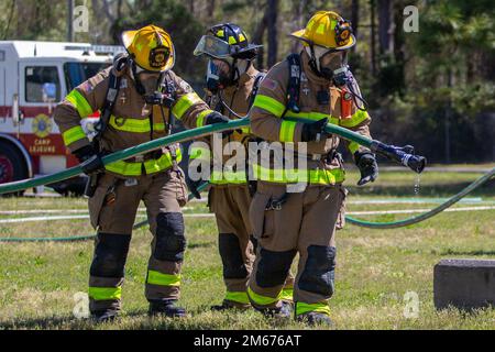 Owen Fowler, links, Jeremy Cain, Mitte, und Ethan Harris, Alle Feuerwehrleute aus Camp Lejeune, Feuerwehr und Rettungsdienst, leiten Sie eine praktische Flughafenfeuerwehr auf dem Marinekorps-Basislager Lejeune, North Carolina, ab, 9. April 2022. Alle Mitarbeiter von Camp Lejeune Fire and Emergency Services müssen eine Feuerwehrzertifizierung am Flughafen erhalten, um jede Mission an Bord der Marine Corps Air Station New River zu unterstützen. Stockfoto