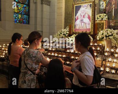 Manila, Philippinen. 02. Januar 2023. Eine Familie zündet Kerzen an, um dem späten Pontifex Benedict XVI. Letzten Respekt zu zollen Katholische Anhänger zollen Papst Emeritus Benedict XVI ihren letzten Respekt, indem sie Gebete aussprechen, Kerzen anzünden und am Montag, den 2. Januar, das Beileidsbuch für den späten Pontifex in der Christus-Königskapelle der Kathedrale von Manila schreiben. Der verstorbene Papst, dessen Geburtsname Joseph Aloisius Ratzinger war, starb letzten 31. Dezember 2022 im Alter von 95 Jahren im Kloster Hook Ecclesiae in der Vatikanstadt. Kredit: SOPA Images Limited/Alamy Live News Stockfoto