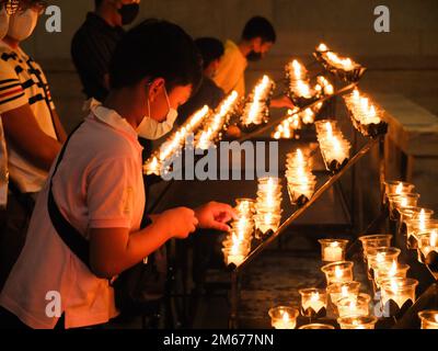 Manila, Philippinen. 02. Januar 2023. Ein Junge zündet eine Kerze an, um dem verstorbenen Papst Emeritus Benedict XVI. Seinen letzten Respekt zu zollen Katholische Anhänger zollen Papst Emeritus Benedict XVI ihren letzten Respekt, indem sie Gebete aussprechen, Kerzen anzünden und am Montag, den 2. Januar, das Beileidsbuch für den späten Pontifex in der Christus-Königskapelle der Kathedrale von Manila schreiben. Der verstorbene Papst, dessen Geburtsname Joseph Aloisius Ratzinger war, starb letzten 31. Dezember 2022 im Alter von 95 Jahren im Kloster Hook Ecclesiae in der Vatikanstadt. Kredit: SOPA Images Limited/Alamy Live News Stockfoto