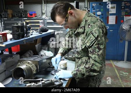 NORFOLK, VA (11. April 2022) Gunner's Mate 3. Class Anthony Pecoraio aus Philadelphia, Pennsylvania, trägt Schmiermittel auf eine Getriebebaugruppe auf, während sie in der Gun Shop des regionalen Wartungszentrums für den Mittelatlantik arbeitet. Stockfoto