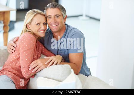 Ich kann mir keine bessere Möglichkeit vorstellen, den Tag zu verbringen... Porträt eines liebevollen, erwachsenen Paares, das sich zu Hause auf dem Sofa entspannt. Stockfoto