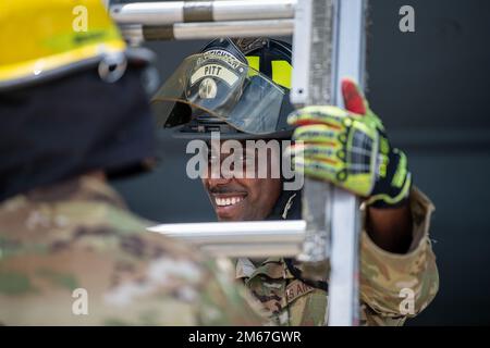 Senior Airman Walter Pitt, 18. Civil Engineer, Squadron Fire Defighter, stabilisiert eine Leiter, während ein weiterer 18. CES-Feuerwehrmann während des Trainings am Kadena Air Base, Japan, am 12. April 2022 auf einen 909. Air Tanken Squadron KC-135 Stratotanker Flügel klettert. 18. die Feuerwehrleute der CES suchten bei einem simulierten Cockpit- oder Triebwerksbrand nach "nicht verbuchten Personen", um ihre Rettungs- und Wiederherstellungsfähigkeiten zu testen. Stockfoto