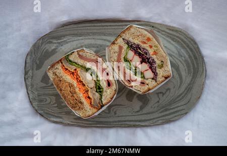 Hausgemachte Sandwichs gefüllt mit Schinken, Käse, Krabbenstäbchen, Schweinefleisch, Mayonnaise, Getrocknetes Schweineschredder, Purpurkohl und Gemüsemischungen auf Keramik t Stockfoto