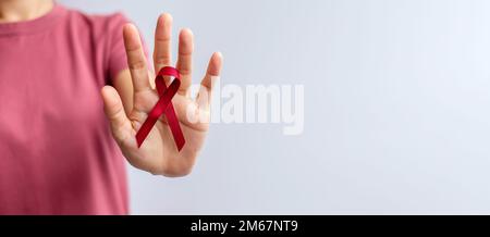 Burgundisches rotes Band für den März des Multiplen Myelom-Krebses und den Dezember des Welt-Aids-Tages-Bewusstseinsmonats. Konzept des Tages des Gesundheitswesens und des Weltkrebses Stockfoto