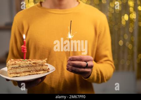 Mann mit leckerem Kuchen, Kerze und Glitzer, Nahaufnahme Stockfoto