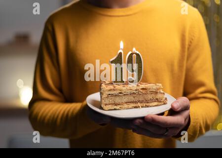 Kuchen mit der Nummer 19 brennenden Kerzen in Männerhänden. Zum 19. Geburtstag Stockfoto