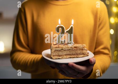 Kuchen mit der Nummer 21 brennenden Kerzen in Männerhänden. Zum 21. Geburtstag Stockfoto