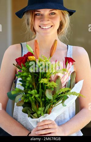 Die Erde lacht in Blumen. Eine junge Frau mit einem Blumenstrauß. Stockfoto