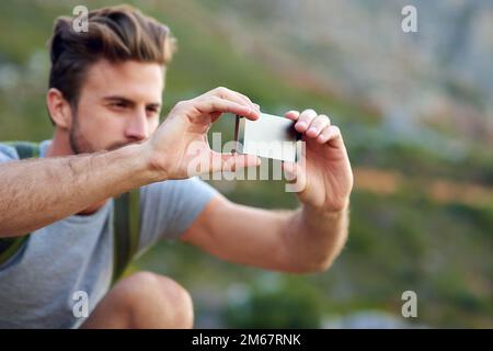 Ich mache ein paar Aufnahmen für die Leute zu Hause. Ein gutaussehender junger Mann, der beim Wandern Fotos macht. Stockfoto
