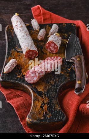 Fermentierte Salami-Würste auf einem in Scheiben geschnittenen Holzbrett Stockfoto