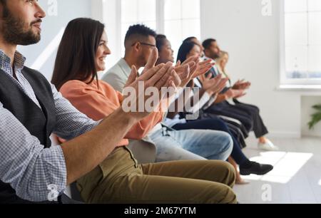 Eine Gruppe zufriedener Männer und Frauen in der Reihe applaudiert bei einer Geschäftskonferenz oder einem Teammeeting. Stockfoto