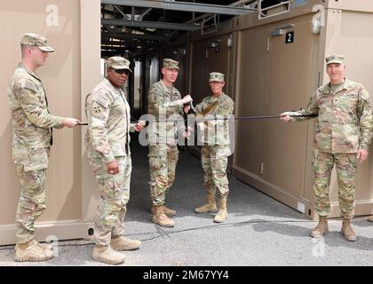 Brigg. General Lance G. Curtis, Stellvertretender General, 1. Theater Sustainment Command, und LT. Oberstleutnant Wendra J. Galfrand, ein Arzt der Area Support Group-Kuwait, bereiten sich darauf vor, das Band während einer Zeremonie zur Eröffnung der neuen Isolierungsanlage in Camp Arifjan, Kuwait, am 14. April 2022 zu schneiden. Die aktualisierte Einrichtung ist eine modernisierte Version der Isolationseinrichtungen, die traditionell Streitkräfte in US-Lagern in Kuwait dienten und die Fähigkeit erweitern, zukünftige Krankheitsausbrüche innerhalb der Anlage zu mildern. Stockfoto