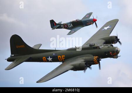 Boeing B-17 Flying Fortress Memphis Belle und North American Mustang P-51D fliegen in Formation in Duxford, Großbritannien Stockfoto