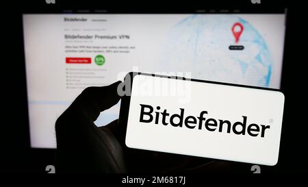 Person, die ein Mobiltelefon mit dem Logo des rumänischen Cybersicherheitsunternehmens Bitdefender auf dem Bildschirm vor der Unternehmenswebseite hält. Konzentrieren Sie sich auf das Display des Telefons. Stockfoto