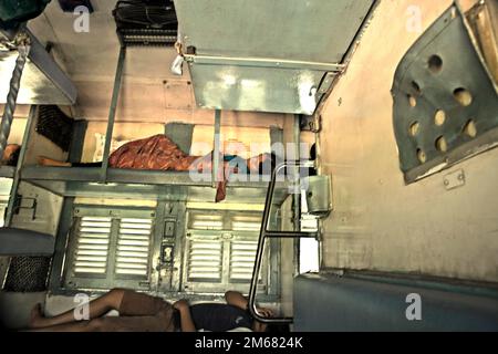 Passagiere, die in der Schlafkurse des indischen Bahndienstes schlafen; fotografiert am Bahnhof von Neu-Delhi in Delhi, Indien. Stockfoto