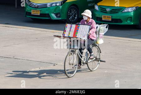 SAMUT PRAKAN, THAILAND, FEBRUAR 23 2022, Eine Lotterieverkäuferin fährt Fahrrad Stockfoto