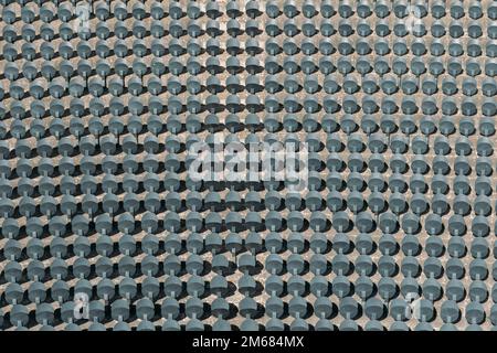 Graue Klappsitze auf den Tribünen eines großen Stadions im Freien, Draufsicht. Sitze für Fans ihrer Lieblingsteams. Leere Plastikstühle für Sportarenen Stockfoto