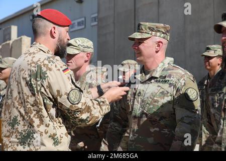 Major Christoph Hänsel, der stellvertretende hochrangige nationale Vertreter für Deutschland, stiftete während einer Verleihung der Auszeichnung der deutschen Streitkräfte auf der Basis der Union III Forward Operating Base in Bagdad, Irak, am 15. April 2022 ein US-Soldat mit dem Abzeichen der deutschen Streitkräfte. Das deutsche Bundeswehrabzeichen wird an Soldaten vergeben, die in der Kampfkunst befähigt sind, und ist ein offizieller Militärpreis, der nur von eingesammelten Wehrmitgliedern getragen werden darf. AdviseAssistEnable, StrongerTogether, Stockfoto