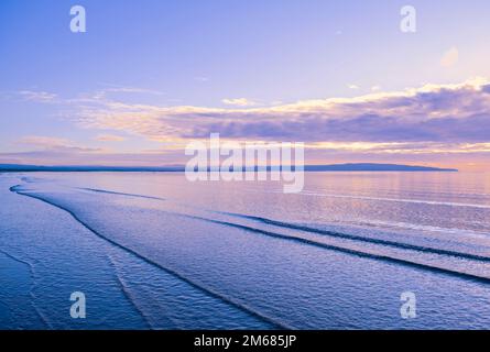 Die Landzunge von Ayr in der Ferne fast in Silhouette und von der Bucht von Troon mit Reflexionen auf dem Wasser Stockfoto