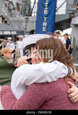 NORFOLK (16. April 2022) - Ein Matrose, der dem Arleigh Burke-Klasse-Guided-Missile Destroyer USS Mitscher (DDG 57) zugeteilt wurde, umarmt seine Frau nach der Rückkehr des Schiffes zum Homeport, Marinestützpunkt Norfolk, April 16. Mitscher entsandte sich in das europäische Operationstheater und nahm an einer Reihe von maritimen Aktivitäten zur Unterstützung der Marinestreitkräfte Europa und der NATO-Alliierten Teil. Stockfoto