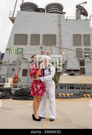 NORFOLK (16. April 2022) - Ein Matrose, der dem Arleigh Burke-Klasse-Guided-Missile Destroyer USS Mitscher (DDG 57) zugeteilt wurde, umarmt seine Frau nach der Rückkehr des Schiffes zum Homeport, Marinestützpunkt Norfolk, April 16. Mitscher entsandte sich in das europäische Operationstheater und nahm an einer Reihe von maritimen Aktivitäten zur Unterstützung der Marinestreitkräfte Europa und der NATO-Alliierten Teil. Stockfoto