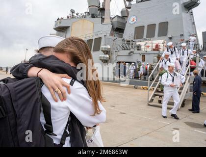 NORFOLK (16. April 2022) - Ein Matrose, der dem Arleigh Burke-Klasse-Guided-Missile Destroyer USS Mitscher (DDG 57) zugeteilt wurde, umarmt seine Frau nach der Rückkehr des Schiffes zum Homeport, Marinestützpunkt Norfolk, April 16. Mitscher entsandte sich in das europäische Operationstheater und nahm an einer Reihe von maritimen Aktivitäten zur Unterstützung der Marinestreitkräfte Europa und der NATO-Alliierten Teil. Stockfoto