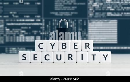 Wörter zur Cybersicherheit auf Würfelblöcken, geschlossenes Vorhängeschloss und Computerdatenbildschirm im Hintergrund Stockfoto