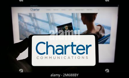 Person, die ein Smartphone mit dem Logo des US-Medienunternehmens Charter Communications Inc. Auf dem Bildschirm vor der Website hält. Konzentrieren Sie sich auf das Display des Telefons. Stockfoto