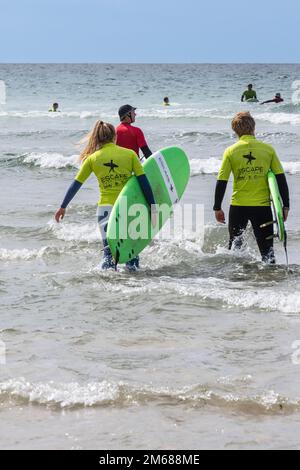 Urlauber nehmen an einer Surfstunde mit einem Lehrer am Fistral Beach in Newquay in Cornwall in Großbritannien Teil. Stockfoto