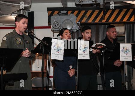 SEELEUTE AUS DEM PHILIPPINISCHEN MEER (17. April 2022) singen als Teil eines Chors während des römisch-katholischen Osterdienstes an Bord des Flugzeugträgers der Nimitz-Klasse USS Abraham Lincoln (CVN 72). Die Abraham Lincoln Strike Group befindet sich in einem geplanten Einsatz im US-7.-Flottenbereich, um die Interoperabilität durch Allianzen und Partnerschaften zu verbessern und gleichzeitig als einsatzbereite Truppe zur Unterstützung einer freien und offenen Region Indo-Pacific zu fungieren. Stockfoto